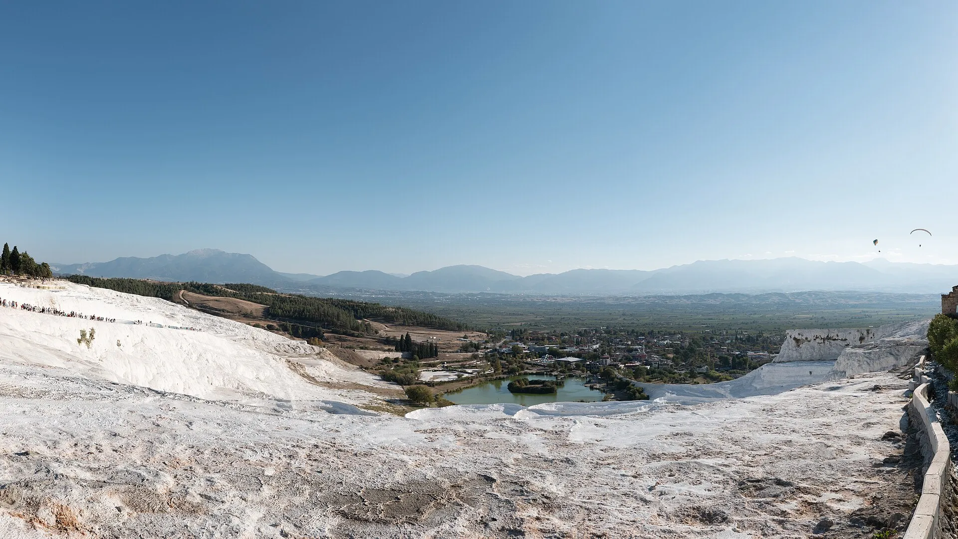 The white travertine terraces of Pamukkale on a quiet day, with few people on the slope