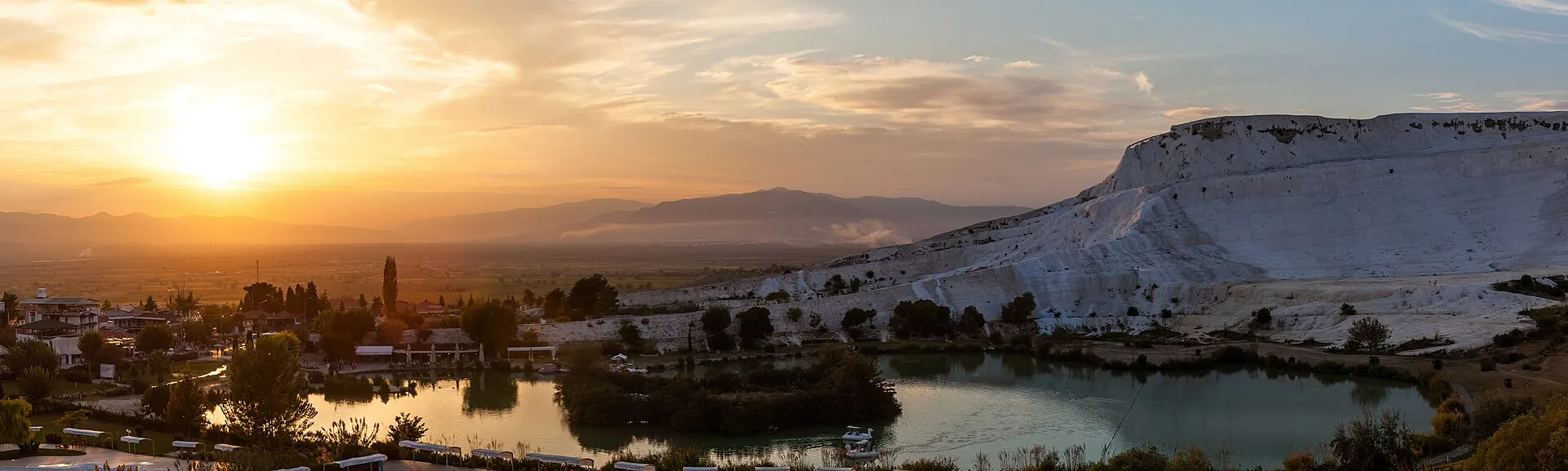 The Pamukkale travertine terraces turning gold at sunset with few people on the slope