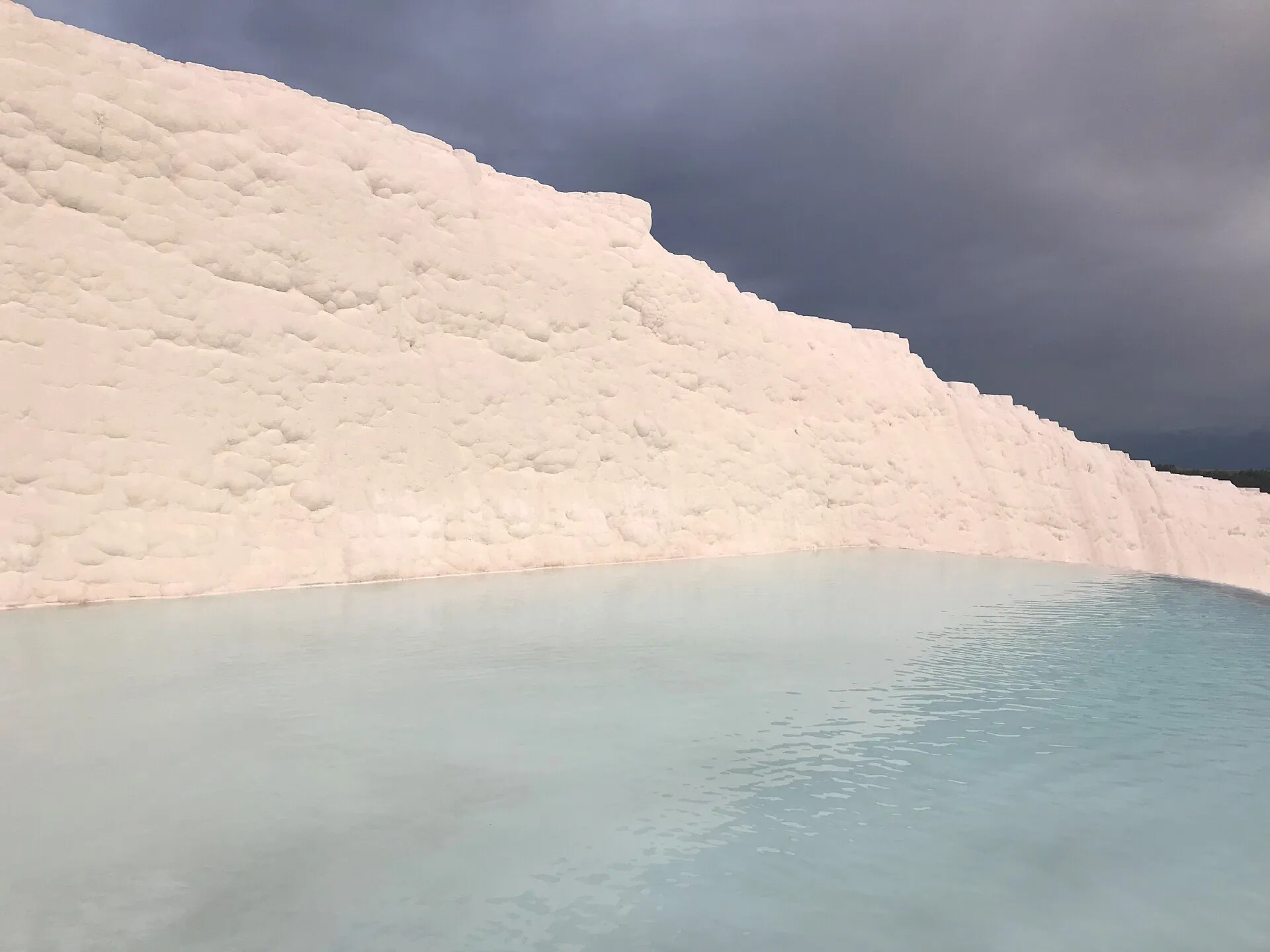 Close-up of the ridged white travertine surface at Pamukkale with thermal water running over the rim