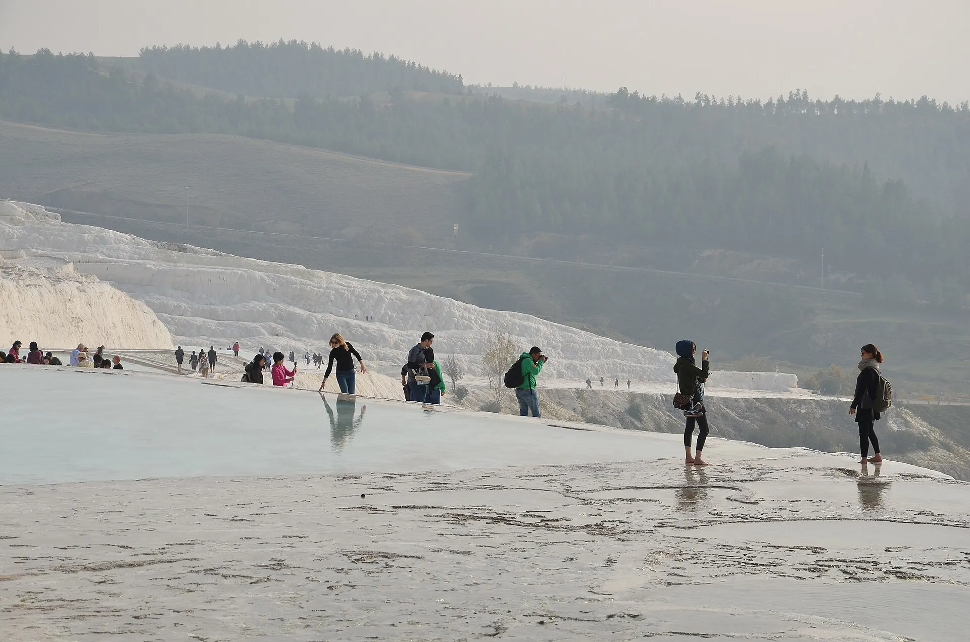 The broad white travertine terraces of Pamukkale with visitors walking across the pale rock