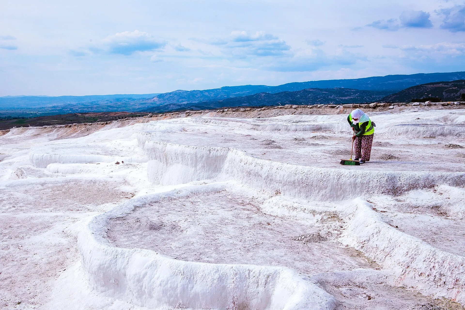 Visitors walking barefoot along the marked path on Pamukkale's water-filled travertine terraces